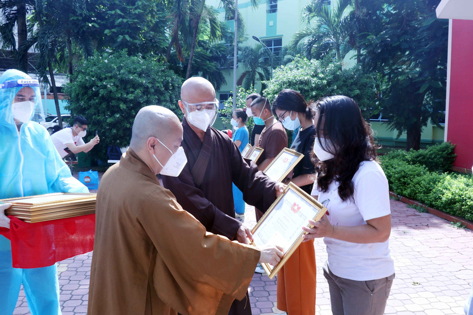 Thượng tọa Thích Thiện Quý, Phó Trưởng ban kiêm Chánh Thư ký Ban Trị sự Giáo hội Phật giáo Việt Nam Thành phố Hồ Chí Minh và Thượng tọa Thích Nhật Từ, Phó Viện trưởng Thường trực Học viện Phật giáo Việt Nam tại Thành phố Hồ Chí Minh trao giấy biểu dương và tặng quà cho các tình nguyện viên tôn giáo. (Ảnh: Xuân Khu/TTXVN)