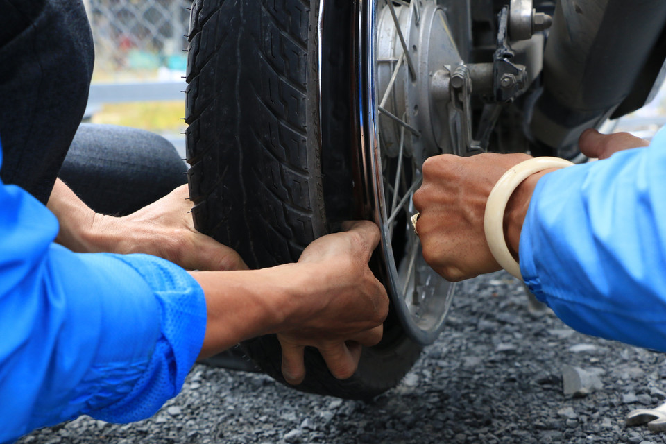 Lực lượng SOS của thanh niên huyện Tháp Mười, tỉnh Đồng Tháp hỗ trợ sửa chữa xe máy miễn phí 24/24 cho người dân trên đường về quê. (Ảnh: Chương Đài/TTXVN)