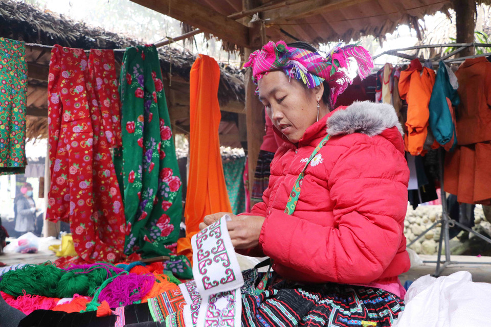 Phụ nữ Mông thêu, may vá khi đang bán hàng. (Ảnh: Nguyễn Oanh/TTXVN)