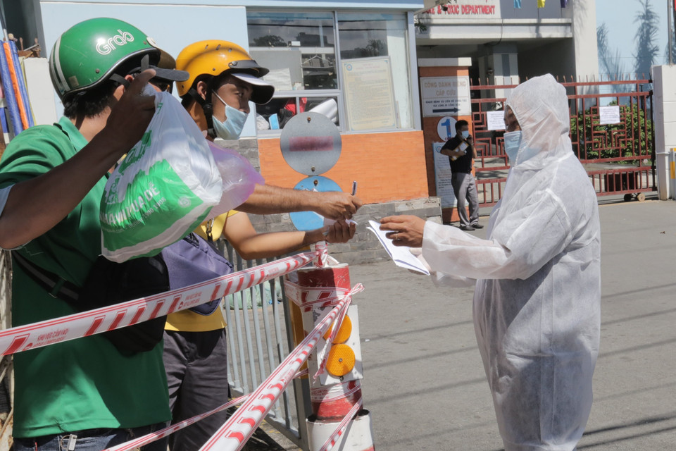 Nhân viên bệnh viện quận Tân Phú hỗ trợ giao nhận nhu yếu phẩm cho bệnh nhân khi bệnh viện bị phong tỏa. (Ảnh: TTXVN phát)