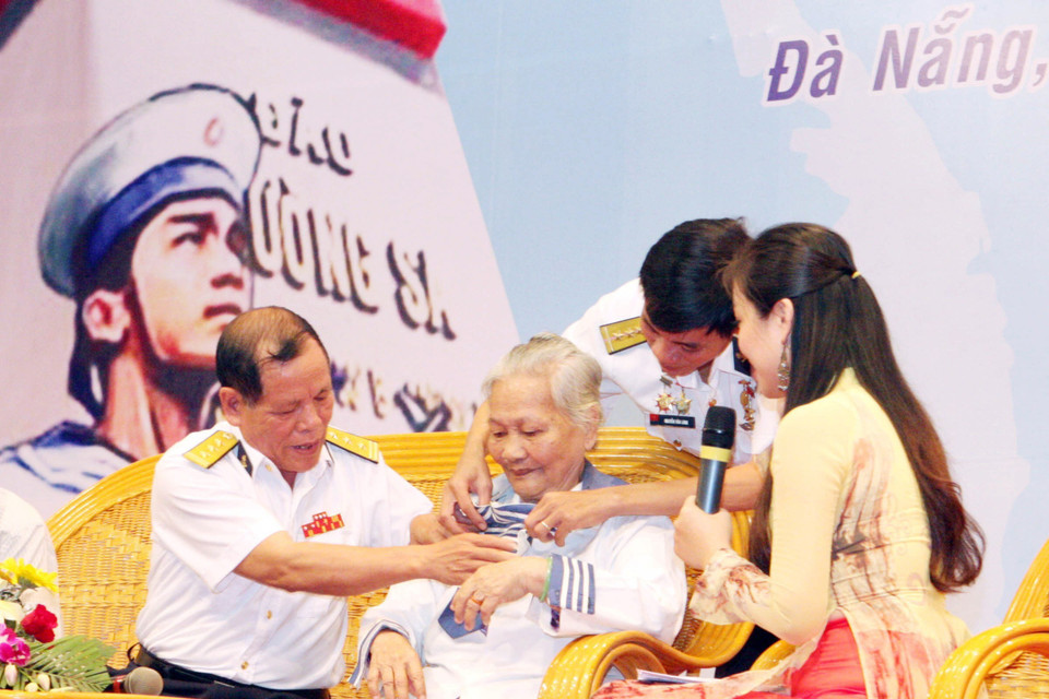 Bà Lê Thị Muộn, mẹ của Liệt sỹ Phan Văn Sự, người đã hy sinh anh dũng trong trận chiến bảo vệ chủ quyền biển đảo Tổ quốc ở Gạc Ma năm 1988, mặc chiếc áo - kỷ vật duy nhất còn lại của người con trai, tại chương trình giao lưu Hướng về Trường Sa thân yêu, ngày 14/3/2013. (Ảnh: Trần Lê Lâm/TTXVN)