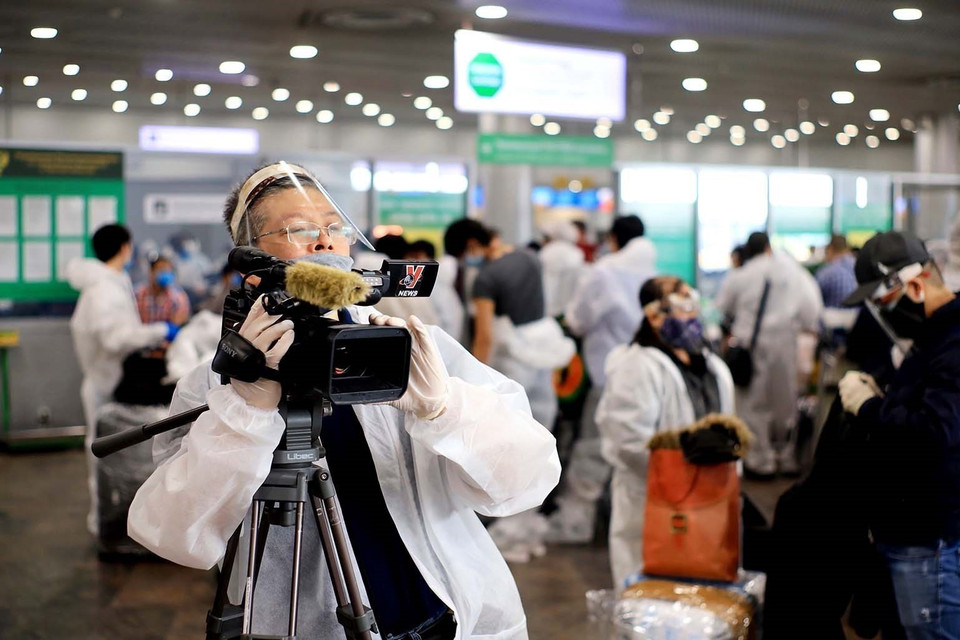 Trưởng Cơ quan thường trú TTXVN tại Moskva Bùi Duy Trinh đưa tin về chuyến bay đầu tiên đưa hơn 300 công dân Việt Nam từ Liên bang Nga về nước trong bối cảnh đại dịch COVID-19, tại sân bay Sheremetyevo, tháng 5/2020. (Ảnh: TTXVN)