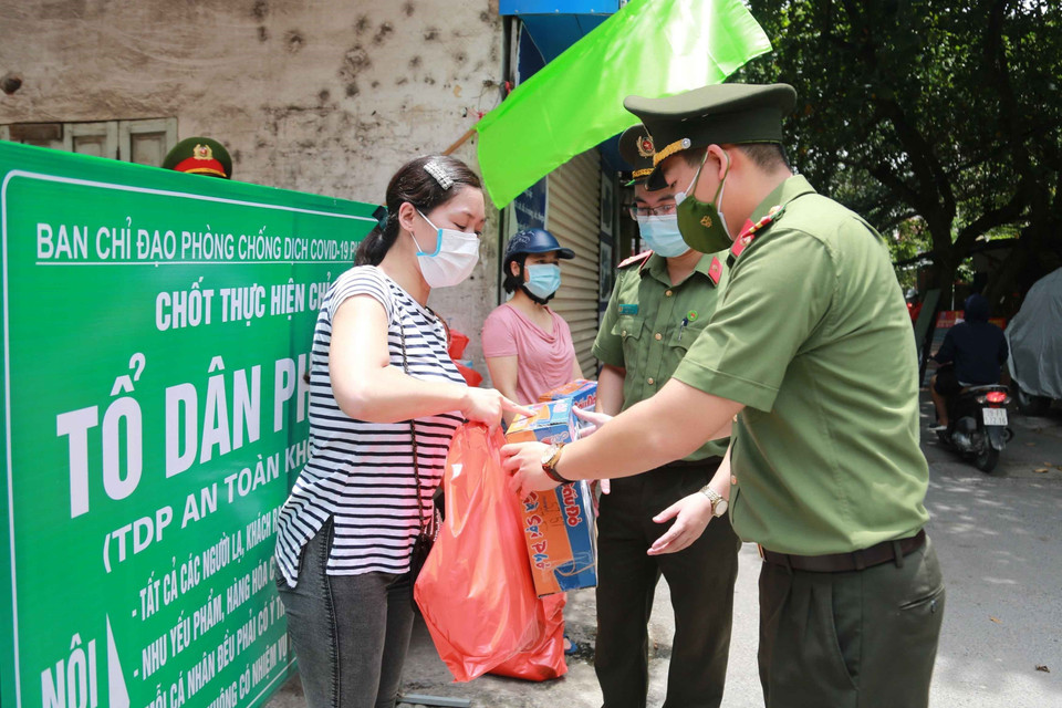 Đại diện Đoàn Thanh niên Công an Hà Nội trao tặng các phần quà cho người dân gặp khó khăn bởi dịch COVID-19. (Ảnh: TTXVN phát)