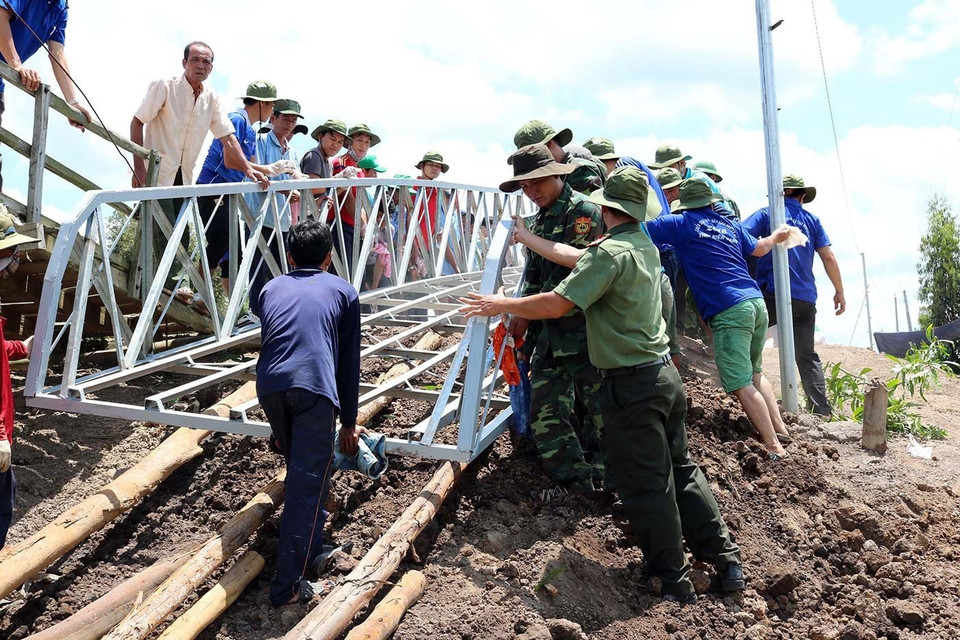 Đoàn viên thanh niên Công an Kiên Giang tham gia làm cầu tại ấp Tràm Trổi, xã Vĩnh Điều, huyện Giang Thành. (Ảnh: Lê Sen/TTXVN)