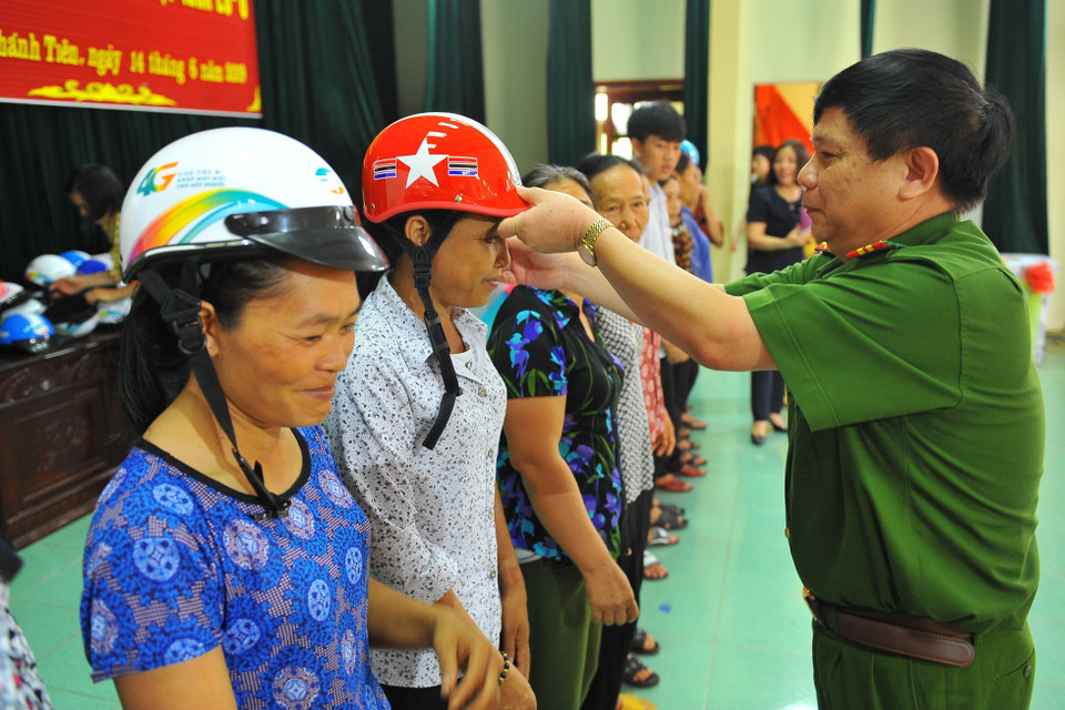Đại tá Vũ Anh Thiều, Phó Giám đốc Công an tỉnh Ninh Bình trao tặng mũ bảo hiểm cho phụ nữ xã Khánh Tiên (huyện Yên Khánh) hưởng ứng ngày gia đình Việt Nam 28/6. (Ảnh: Minh Đức/TTXVN)