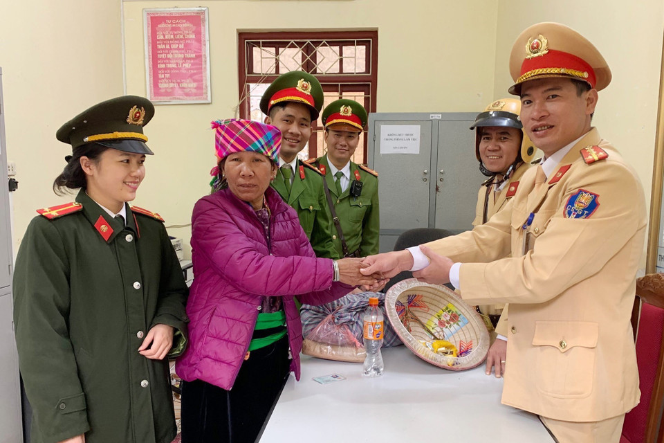Cán bộ, chiến sỹ Công an huyện Mường La, tỉnh Sơn La hỗ trợ nhu yếu phẩm và kinh phí cho bà Đồng Thị Khân (Yên Bái) trở về nhà do bị lạc đường khi đi thăm con. (Ảnh: TTXVN phát)