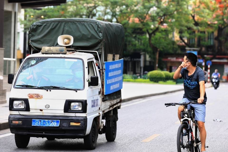 Công an phường Lê Đại Hành gọi loa nhắc nhở người dân ra đường đạp xe tập thể dục, nếu tiếp tục vi phạm sẽ tiến hành xử phạt trong những ngày thành phố thực hiện giãn cách. (Ảnh: Thành Đạt/TTXVN)