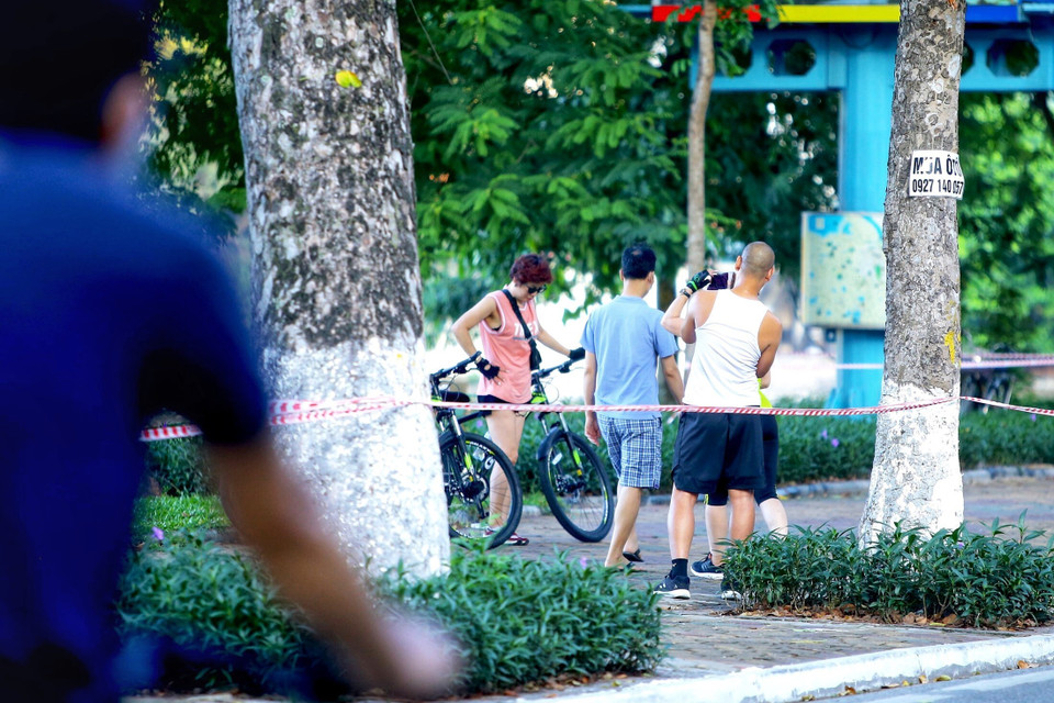 Một số người dân vẫn không đeo khẩu trang, tập thể dục khu vực ven hồ ven hồ Thiền Quang (dù lực lượng Công an phường Nguyễn Du đã căng dây, để biển báo yêu cầu không vi phạm. Ảnh chụp 5h50 ngày 13/7/2021). (Ảnh: Hoàng Hiếu/TTXVN)