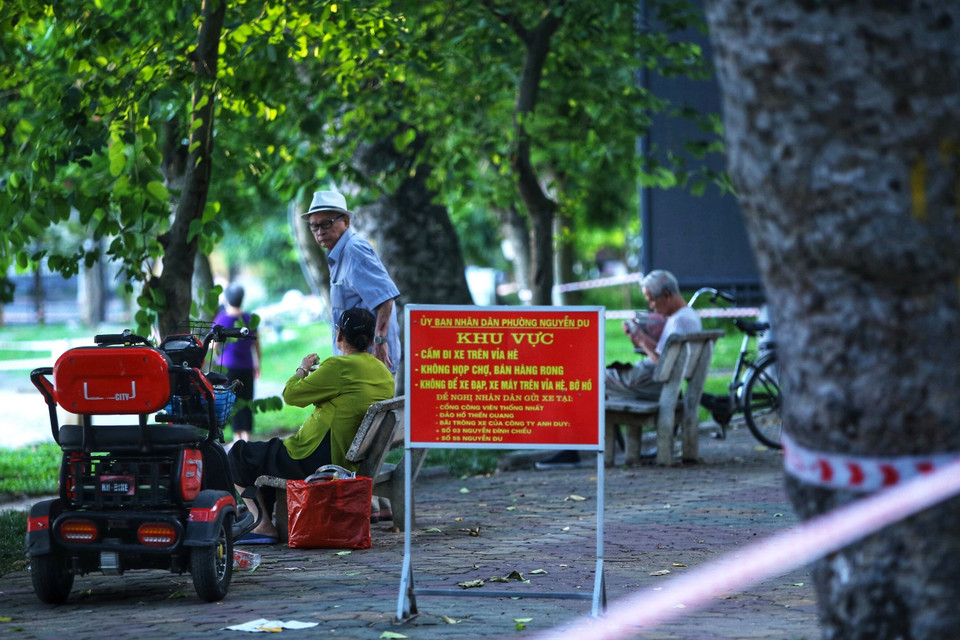 Một số người dân vẫn không đeo khẩu trang, tập thể dục khu vực ven hồ ven hồ Thiền Quang (dù lực lượng Công an phường Nguyễn Du đã căng dây, để biển báo yêu cầu không vi phạm. Ảnh chụp 5h50 ngày 13/7/2021). (Ảnh: Hoàng Hiếu/TTXVN)