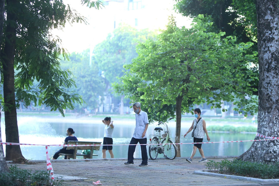 Nhiều người dân vẫn tập thể dục tại khu vực hồ Thiền Quang dù đã được lực lượng chức năng căng dây, cắm biển cấm (ảnh chụp lúc 5h50 ngày 13/7). (Ảnh: Hoàng Hiếu/TTXVN)