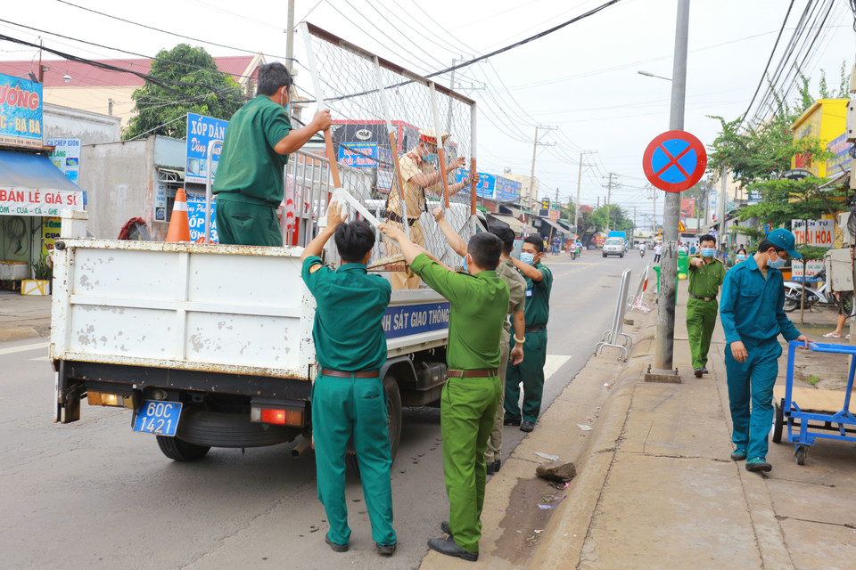 Lực lượng chức năng thực hiện dỡ bỏ phong tỏa cho 20 hộ dân tại khu phố 2, phường Xuân Thanh. (Ảnh: Lê Xuân/TTXVN)