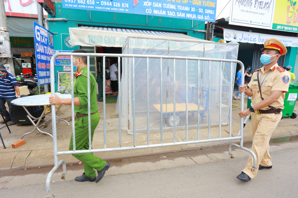 Lực lượng chức năng thực hiện dỡ bỏ phong tỏa cho 20 hộ dân tại khu phố 2, phường Xuân Thanh. (Ảnh: Lê Xuân/TTXVN)