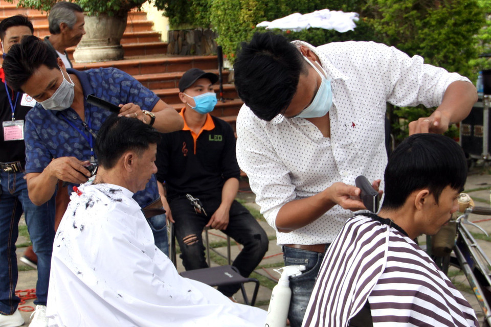 Người dân cắt tóc miễn phí tại Phiên chợ không đồng tổ chức tại Trung tâm bảo tồn di tích Hội An (Quảng Nam). (Ảnh: Trịnh Bang Nhiệm/TTXVN)