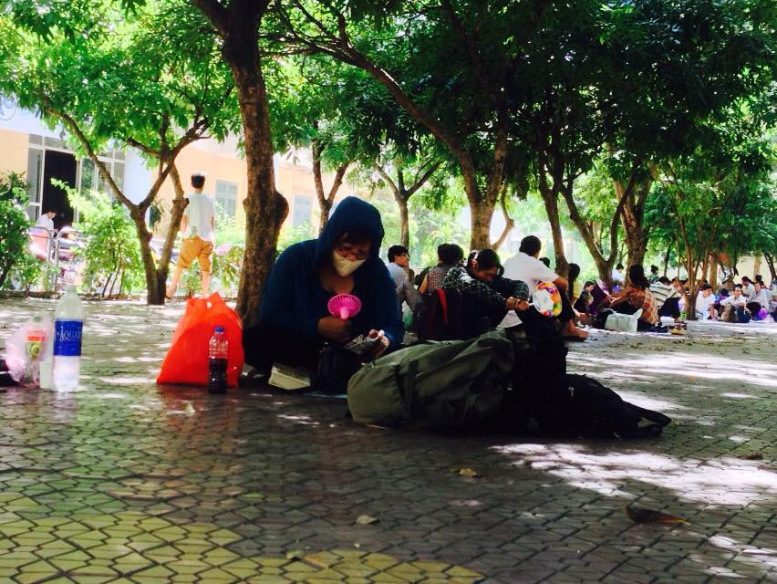 Một phụ huynh tìm cách hạ nhiệt từ quạt mini tại trường Đại học Sư phạm Hà Nội. (Ảnh: Sơn Bách/Vietnam+)