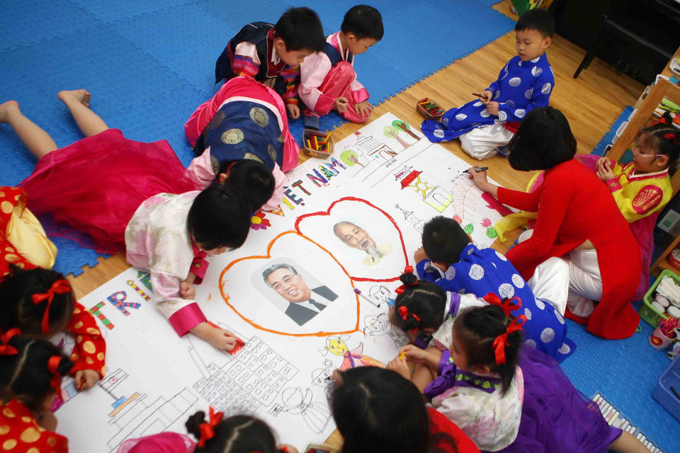 Cô giáo và các bé trong lớp học mang tên Kim Nhật Thành tham gia vẽ bức tranh về chủ đề Tình hữu nghị giữa hai nước Việt Nam- Triều Tiên. (Ảnh: Thanh Tùng/TTXVN)