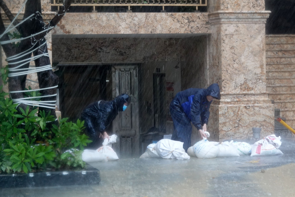 Chủ một khách sạn trên đường ven biển Võ Nguyên Giáp khẩn trương dùng bao cát để chặn nước lối vào hầm. (Ảnh: Quốc Dũng/TTXVN)