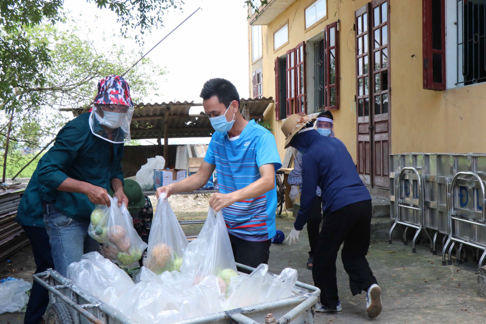 Các tình nguyện viên chuyển thực phẩm lên xe để đi phân phát cho các hộ dân tại xã Mão Điền. (Ảnh: Thanh Thương/TTXVN)