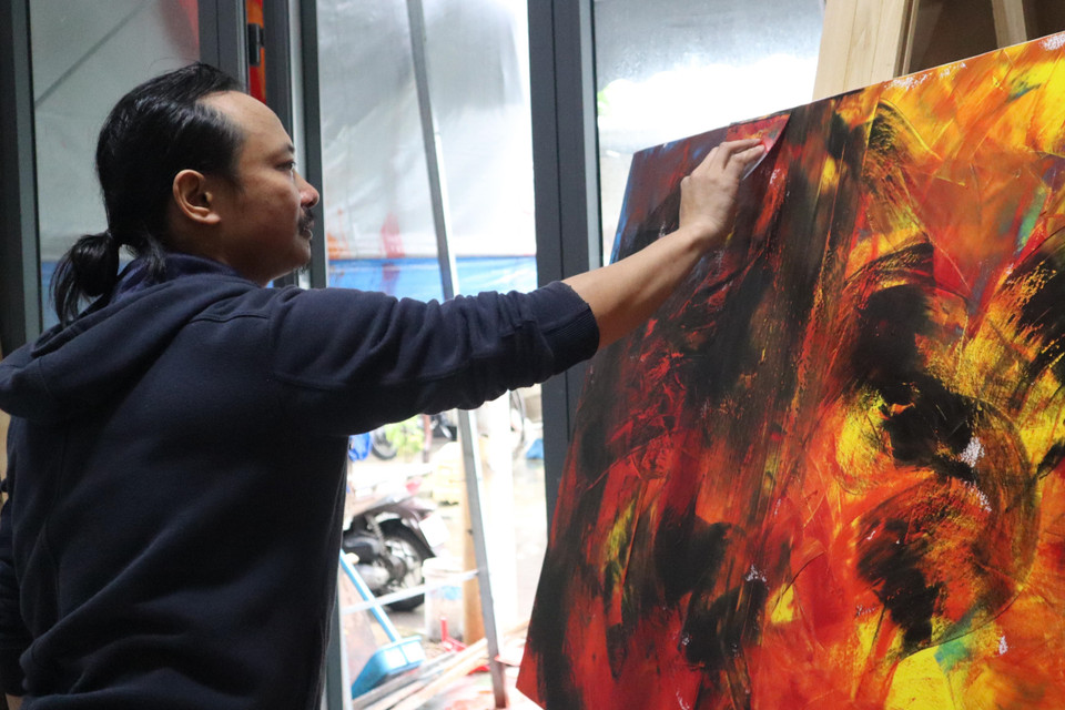 Họa sỹ Ngô Thanh Hùng sáng tác tranh tại nhà. (Ảnh: Văn Dũng/TTXVN)