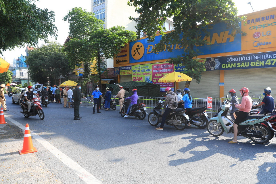 Lực lượng chức năng kiểm tra giấy đi đường của người dân tại chốt số 14 cầu Thạch Bích. (Ảnh: Tuấn Anh/TTXVN)