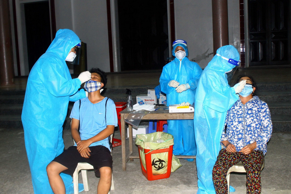 Cán bộ y tế lấy mẫu xét nghiệm cho người dân xã Hưng Đông, thành phố Vinh (Nghệ An) vào tối 20/6. (Ảnh: Tá Chuyên/TTXVN)