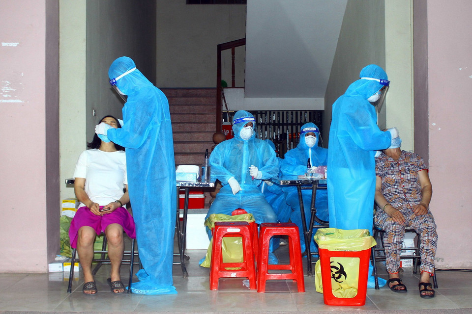 Cán bộ y tế lấy mẫu xét nghiệm cho người dân xã Hưng Đông, thành phố Vinh (Nghệ An) vào tối 20/6. (Ảnh: Tá Chuyên/TTXVN)