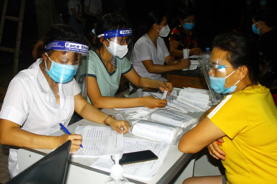 Người dân xã Hưng Đông, thành phố Vinh (Nghệ An) khai báo thông tin trước khi lấy mẫu xét nghiệm COVID-19 vào tối ngày 20/6. (Ảnh: Tá Chuyên/TTXVN)