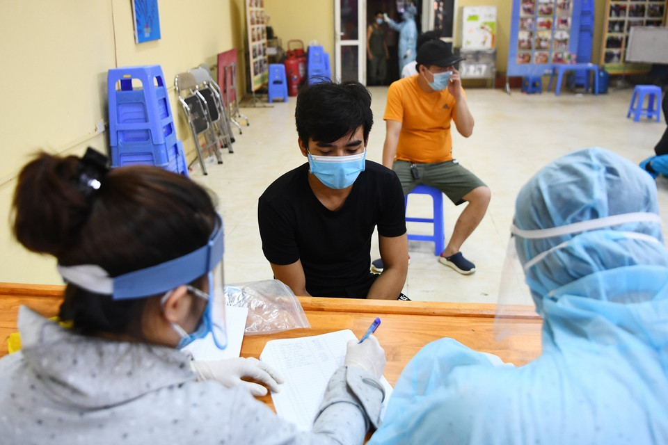 Các tiểu thương chợ Long Biên khai báo y tế trước khi lấy mẫu xét nghiệm. (Ảnh: Thành Đạt/TTXVN)