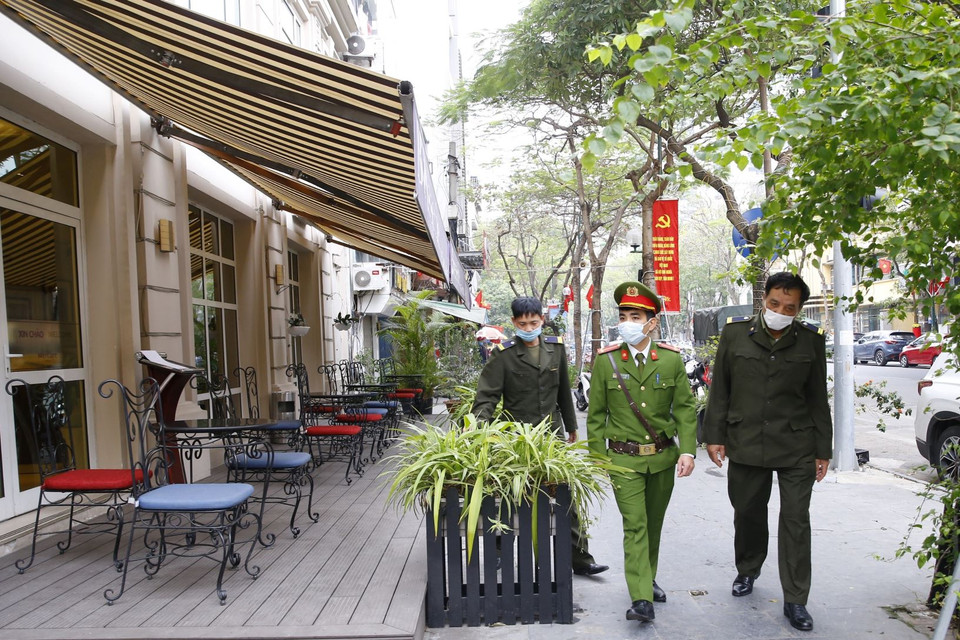 Lực lượng chức năng công an phường Cửa Nam ra quân đề nghị các hộ kinh doanh đóng cửa quán ăn đường phố, trà đá, càphê. (Ảnh: Doãn Tấn/TTXVN)