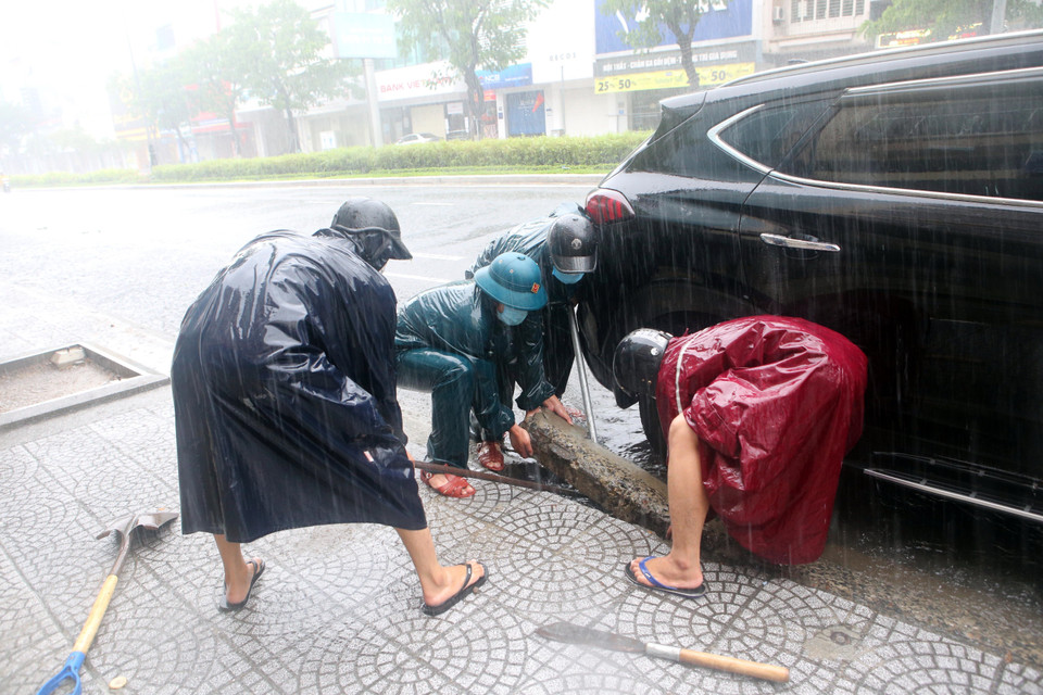 Dân quân phường Nam Dương (quận Hải Châu) tiến hành thông cửa thu nước trên các tuyến đường để chống ngập. (Ảnh: Trần Lê Lâm/TTXVN)