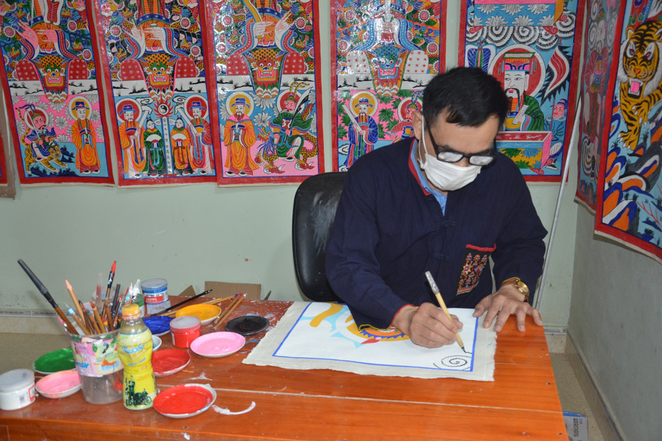 Ông Triệu Hùng Cường đang miệt mài vẽ những bộ tranh thờ với sự cẩn trọng, tỷ mỷ, và sự thấu hiểu về giá trị văn hóa của dân tộc mình qua mỗi bộ tranh. (Ảnh: Hoa Mai/TTXVN)