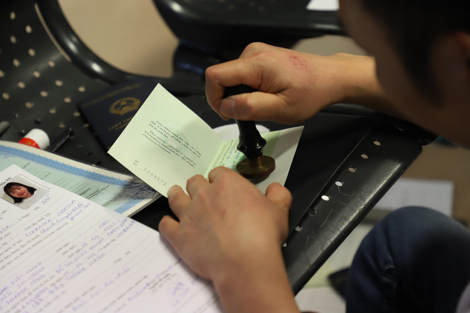 Cán bộ Đại sứ quán Việt Nam đóng dấu, cấp thẻ thông hành cho kiều bào ở sân bay thủ đô Bucharest, Romania. (Ảnh: Mạnh Hùng/TTXVN)