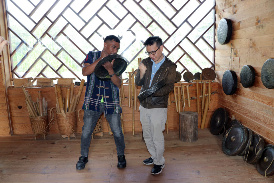 Hướng dân viên du lịch người dân tộc K'Ho giới thiệu cách chơi nhạc cụ dân tộc cho du khách Nhật Bản. (Ảnh: Chu Quốc Hùng/TTXVN)