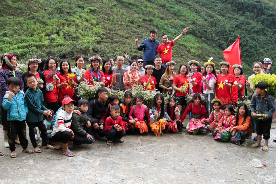 Khách du lịch chụp ảnh cùng các em nhỏ vùng cao tại điểm "check in" Dốc Thẩm Mã. (Ảnh: Nam Thái/TTXVN)