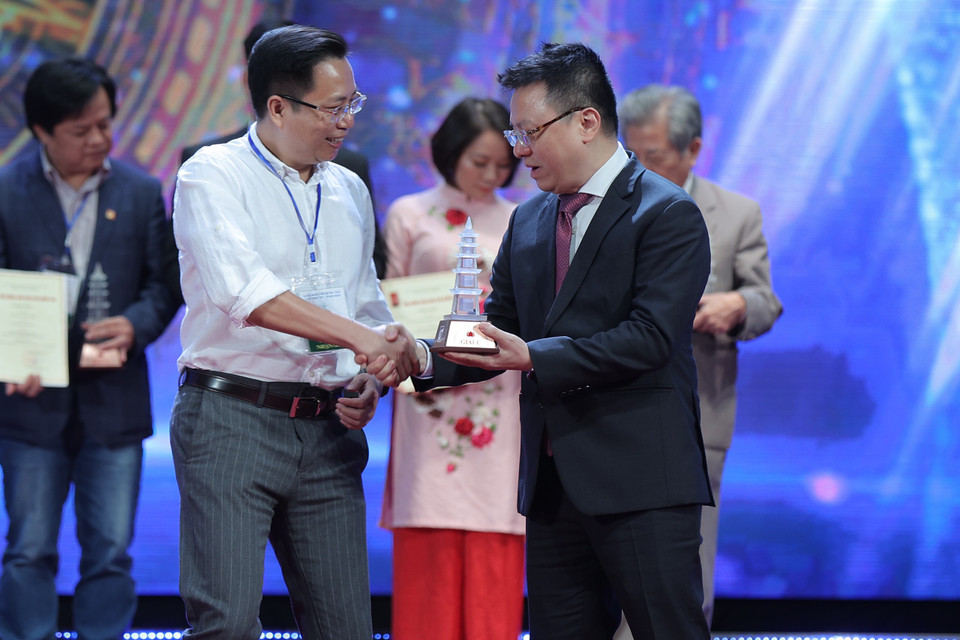 Ông Lê Quốc Minh, Tổng biên tập Báo Nhân dân trao giải cho tác giả. (Ảnh: Hoàng Đạt/Vietnam+)