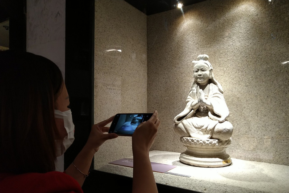 Khách tham quan thích thú trước một hiện vật độc đáo: Tượng Quan Âm men rạn thế kỷ 18. (Ảnh: Minh Thu/Vietnam+)