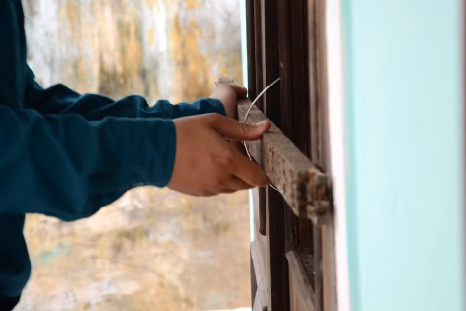 Lực lượng chức năng hỗ trợ các hộ dân gia cố cửa đi, cửa sổ để giảm thiểu tác hại của gió bão. (Ảnh: Quốc Dũng/TTXVN)