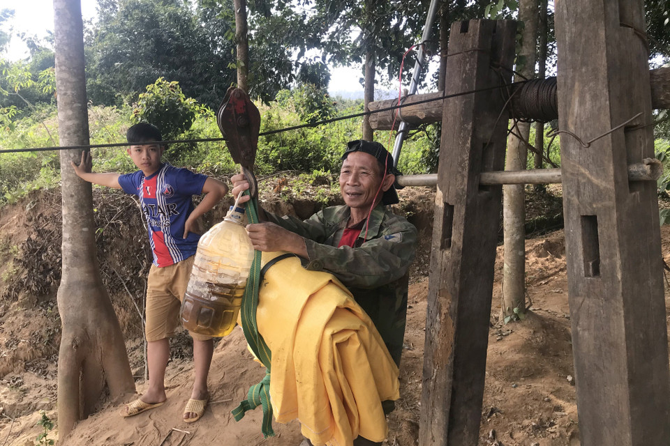 Người dân liều mình đu dây qua sông Pô Kô để mua lương thực. (Ảnh: Khoa Chương/TTXVN)