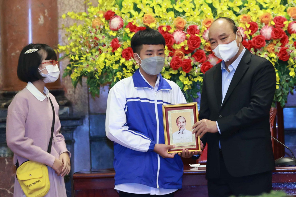 Chủ tịch nước Nguyễn Xuân Phúc tặng chân dung Chủ tịch Hồ Chí Minh cho các học sinh. (Ảnh: Thống Nhất/TTXVN)