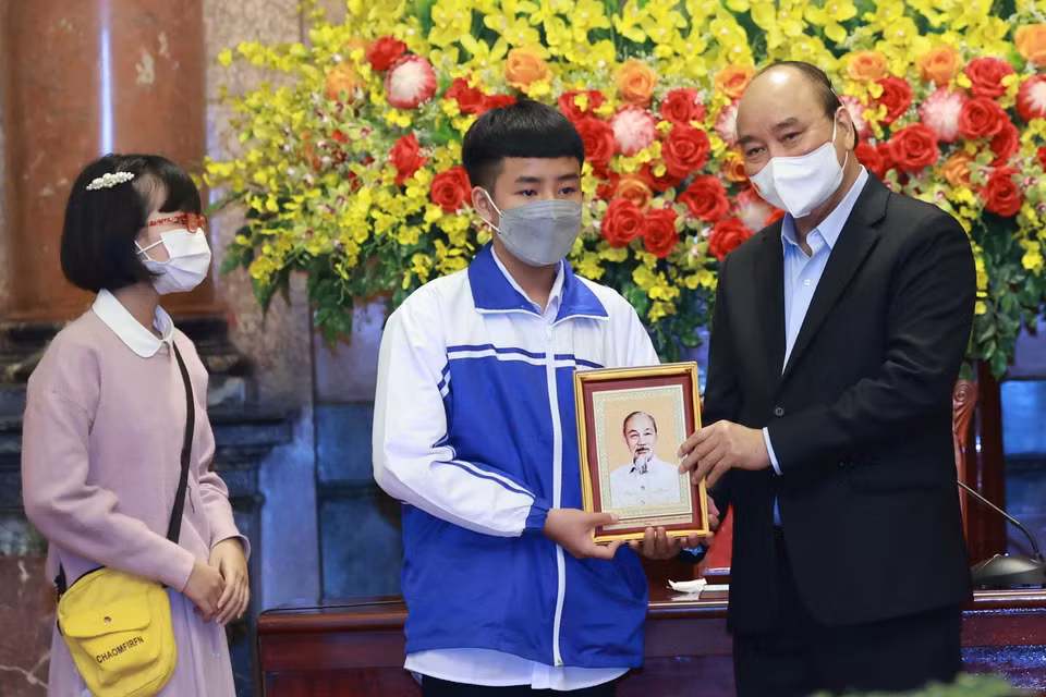 Chủ tịch nước Nguyễn Xuân Phúc tặng chân dung Chủ tịch Hồ Chí Minh cho các học sinh. (Ảnh: Thống Nhất/TTXVN)