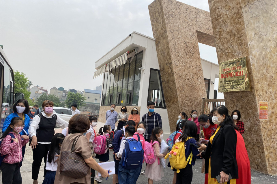 Tại trường Tiểu học Hoàng Mai, Ban giám hiệu, giáo viên trong tà áo dài truyền thống có mặt ở cổng trường từ rất sớm đón các con lần đầu tiên tới ngôi trường mới. Hiệu trưởng nhà trường cho biết đã cố gắng bố trí cho các con học bán trú để cha mẹ có thể yên tâm làm việc. (Ảnh: PV/Vietnam+)