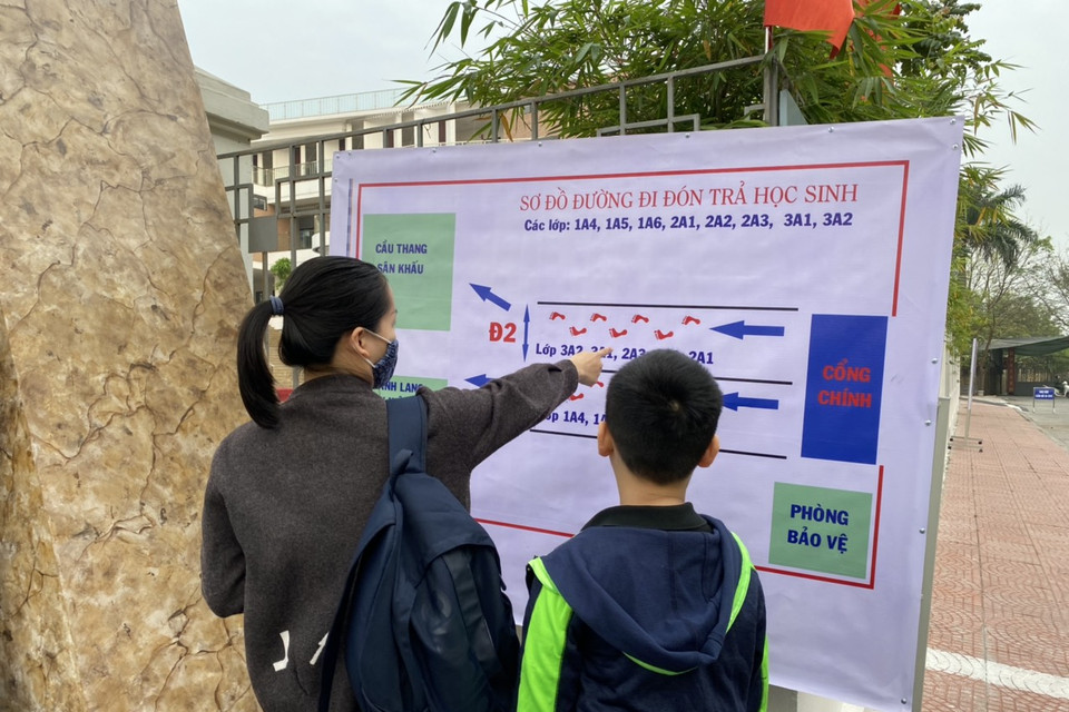 Các lối đi đón, trả học sinh tại Trường Tiểu học Hoàng Mai đều được phân luồng rõ ràng tránh tụ tập đông người. Trong ảnh, một phụ huynh dặn dò con lối đi để thực hiện nội quy của nhà trường. (Ảnh: PV/Vietnam+)