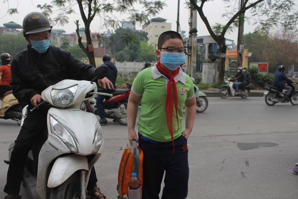 Tại cổng trường tiểu học Phạm Tu, anh Võ Thành Nam đã dặn dò con trai hạn chế tối đa bỏ khẩu trang, lưu ý khử khuẩn tay và các công tác chống dịch theo khuyến cáo của nhà trường. (Ảnh: Minh Anh/Vietnam+)