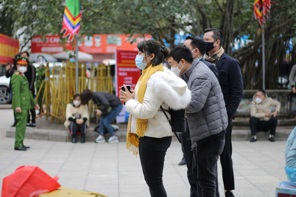 Dưới sự nhắc nhở của lực lượng công an, nhiều người dân chú ý đeo khẩu trang, thực hiện tự sát khuẩn tay và giữ khoảng cách khi đứng lễ. (Ảnh: Minh Anh/Vietnam+)