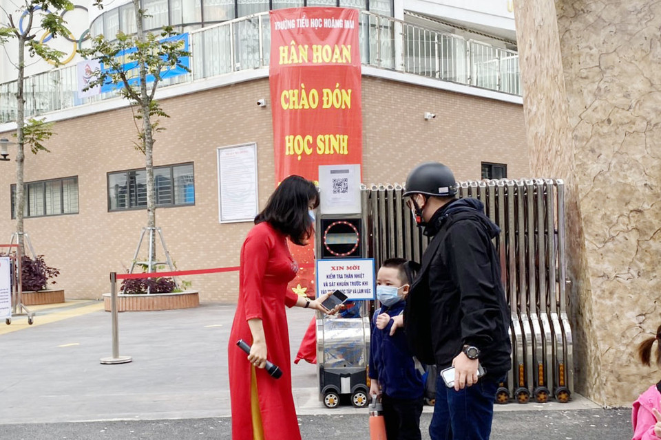 Phụ huynh căn dặn con trước khi cậu bé lớp 1 lần đầu đi học trực tiếp bậc tiểu học. (Ảnh: PV/Vietnam+)