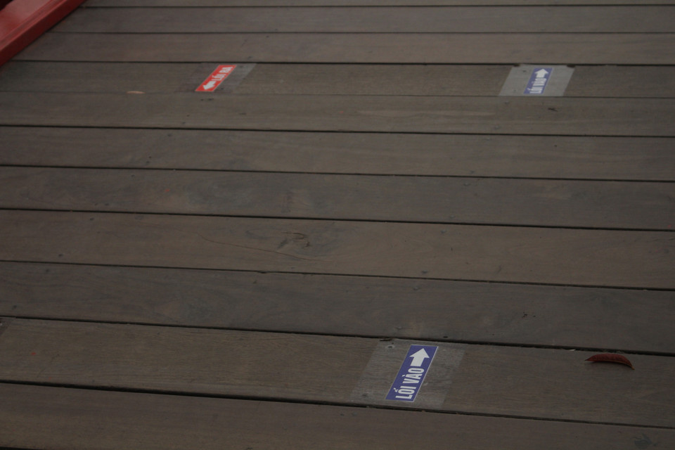 Bên cạnh việc có nhân viên nhắc nhở khách không tụ tập đông người, ban quản lý cũng dán chỉ dẫn trên cầu Thê Húc nhằm phân luồng khách tham quan ra vào đền. (Ảnh: Minh Anh/Vietnam+)