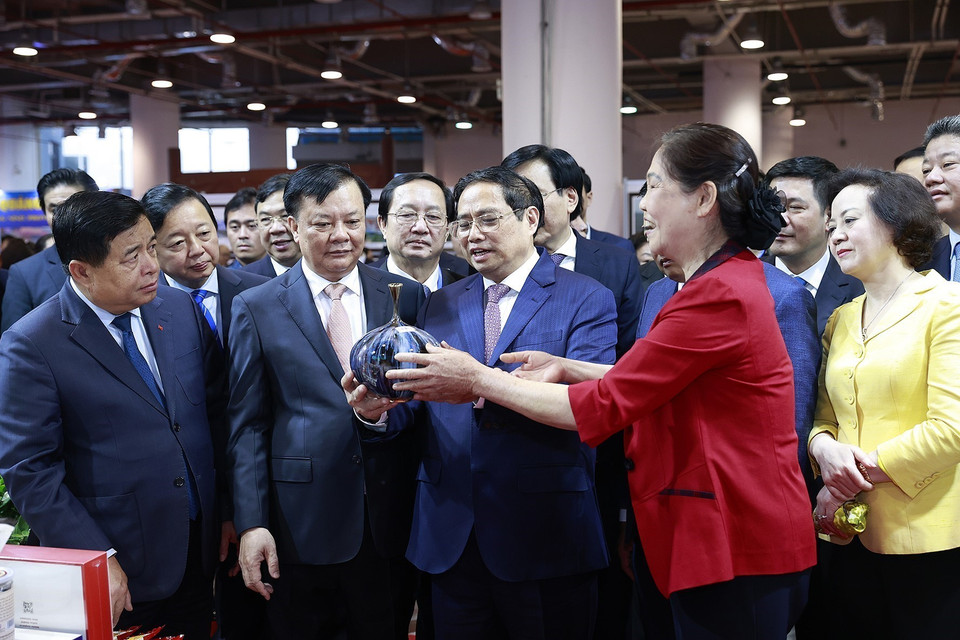 Thủ tướng Phạm Minh Chính xem giới thiệu một sản phẩm thủ công, mỹ nghệ của các tỉnh Đồng bằng sông Hồng. (Ảnh: Dương Giang/TTXVN)