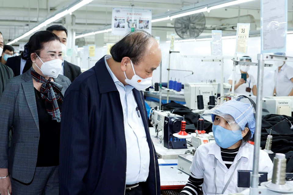Chủ tịch nước Nguyễn Xuân Phúc tham quan, thăm hỏi người lao động tại xưởng sản xuất các sản phẩm dệt may của Công ty cổ phần dệt may 29/3. (Ảnh: Thống Nhất/TTXVN)
