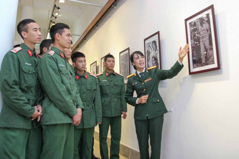 Các chiến sỹ thuộc Bộ Tư lệnh Thủ đô Hà Nội chăm chú nghe hướng dẫn viên giới thiệu các hình ảnh của Triển lãm. (Ảnh Minh Sơn/Vietnam+)