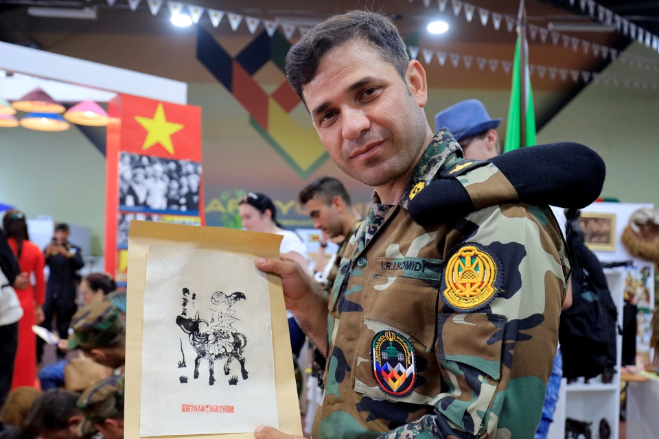 Sỹ quan Ibrahim Homidi vui mừng khi được tìm hiểu về dòng tranh dân gian Đông Hồ trên giấy gió và tự tay hoàn thiện tác phẩm đầu tay của mình. (Ảnh: Trần Hiếu/TTXVN)