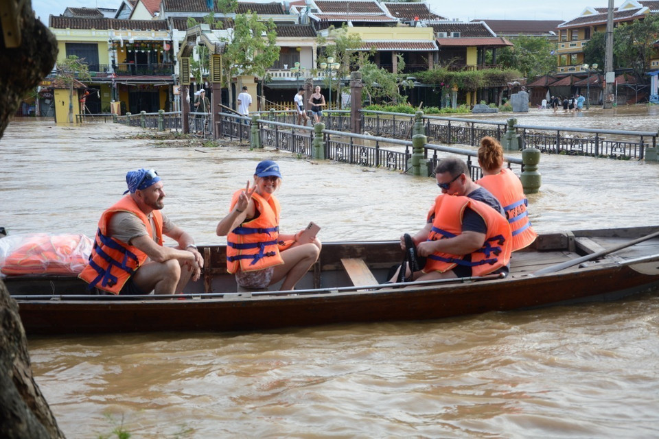 Khách du lịch trải nghiệm cảnh ngập lụt ở phố cổ Hội An. (Ảnh: Văn Dũng/TTXVN)